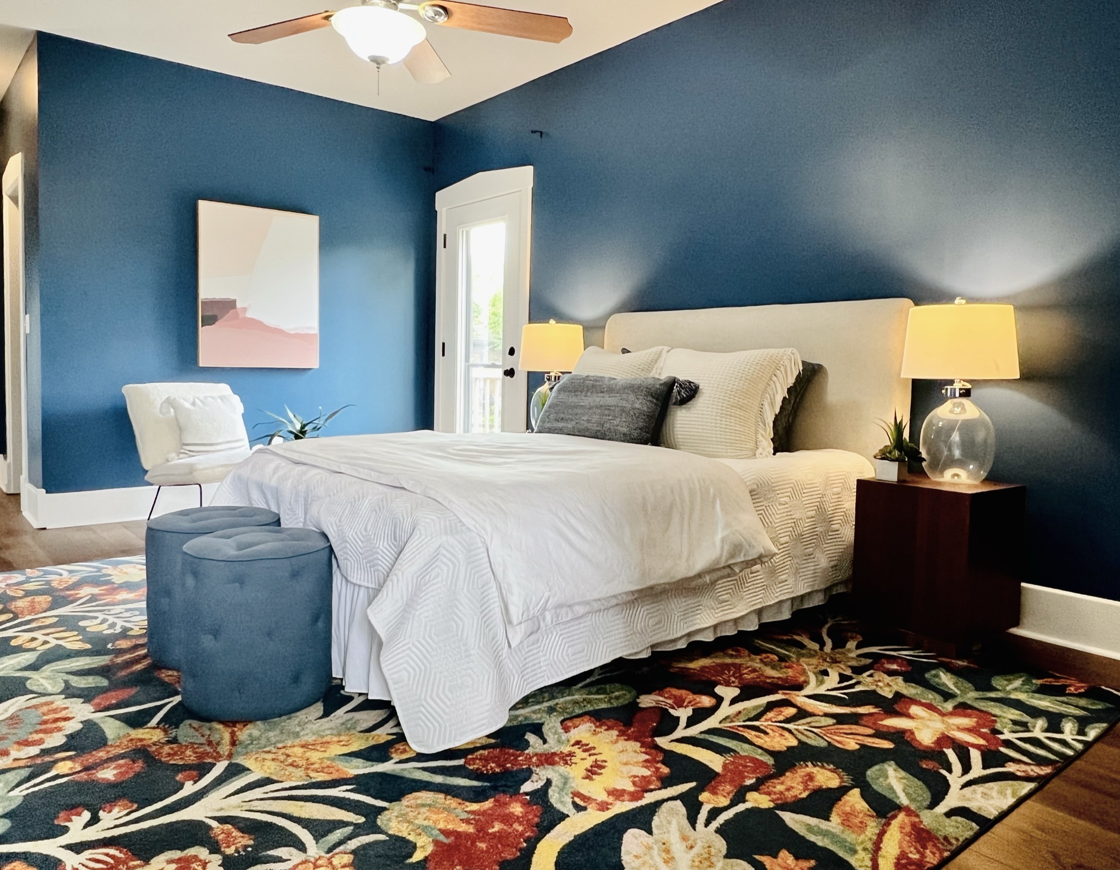 Bedroom with blue walls, white bedding, and hardwood floors
